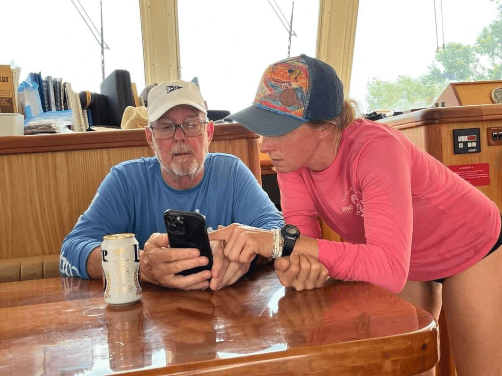 Captain Jodie Knox and her father Robert Knox, aboard Vicarious looking at cell phone