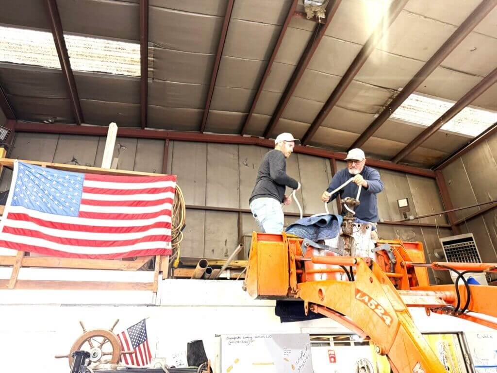Gratitude Marina staff hoist a trawler’s stove by crane out of the boatyard loft