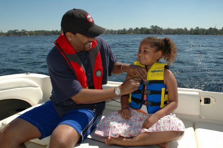 adjusting kid's lifejacket, family in life jackets