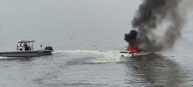 Rescue boat circling a boat on fire