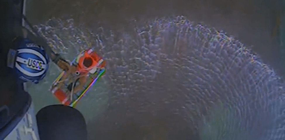 A Coast Guard helicopter crew rescuing three boaters drifting toward a reef after their boat lost power