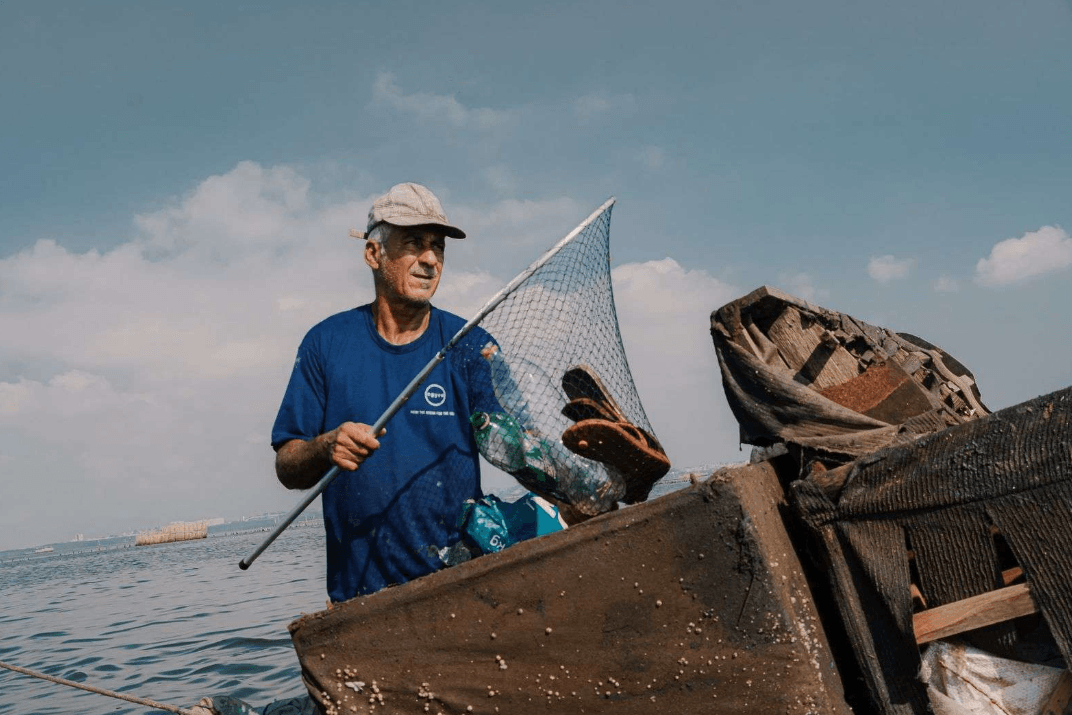 man cleaning trash out of the water