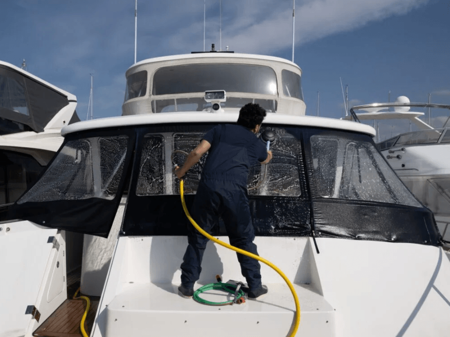 man power washing windows on a boat