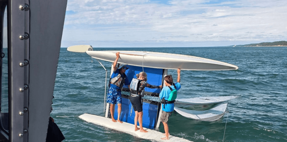 3 people holding up a catamaran