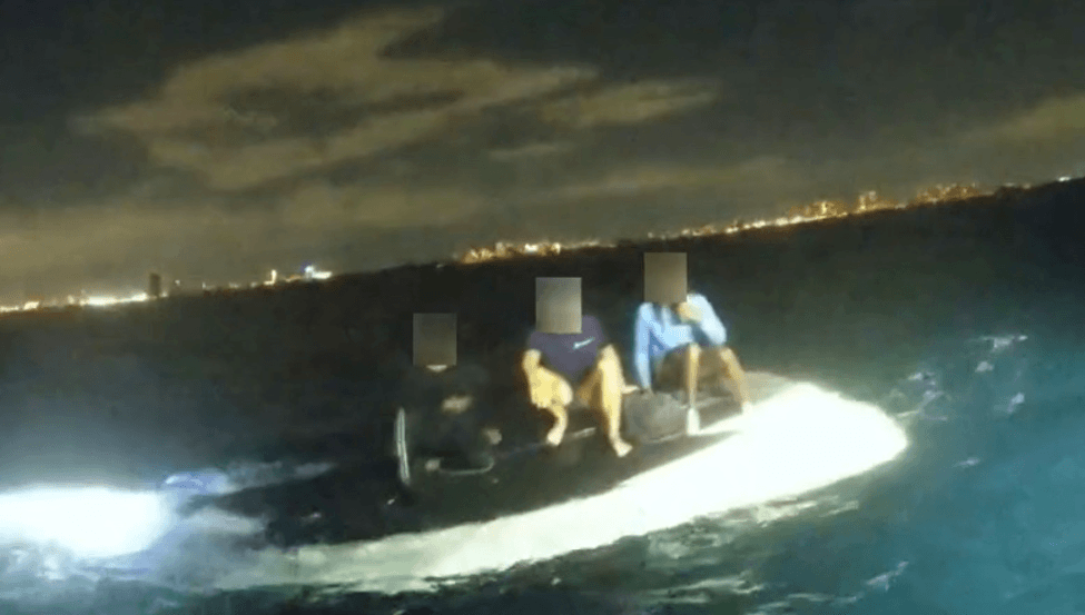 3 Boaters sitting on top of flipped boat