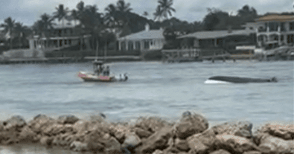 Flipped boat and a rescue vessel on water