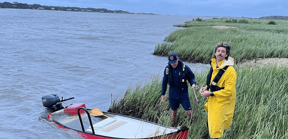 Two men standing next to sinking boat