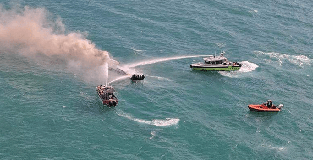 Fire crew putting out a boat fire in ocean