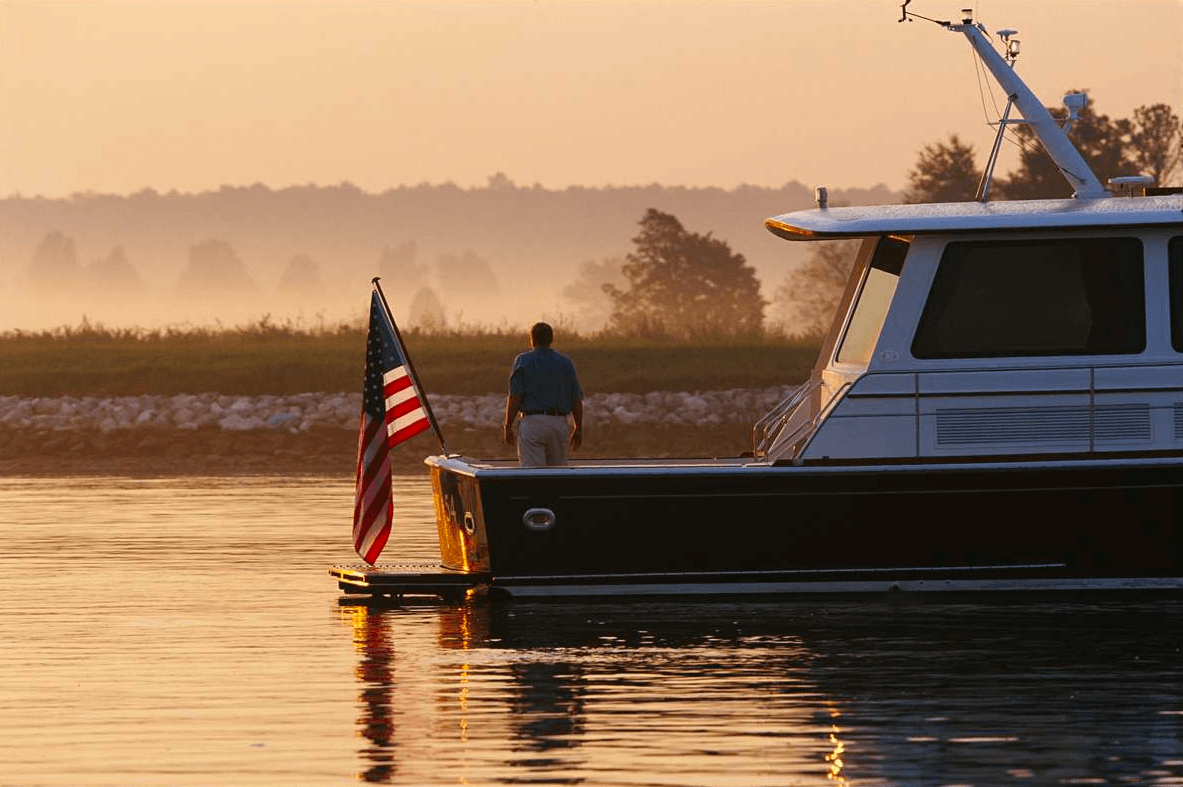 Man, standing on a boat with an American Flag
