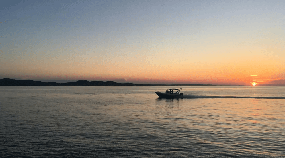 boat running on water with sunset
