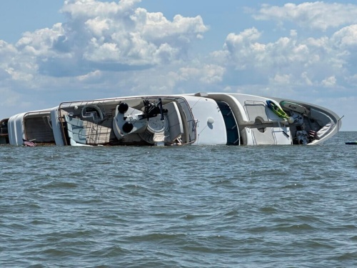 The partially-capsized 122-foot yacht Lovebug sits with its starboard side down in the water.