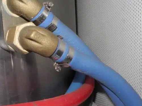 Blue heater hoses bring hot coolant into the water heater tank and return back to the engine after heating the water inside the tank.